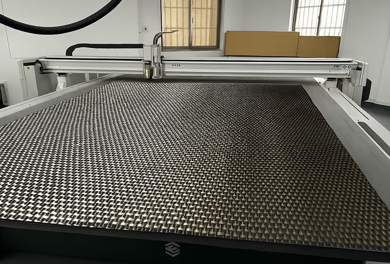 Dyneema 纖維布平鋪於數位切割機床台上，準備進行多層裁切