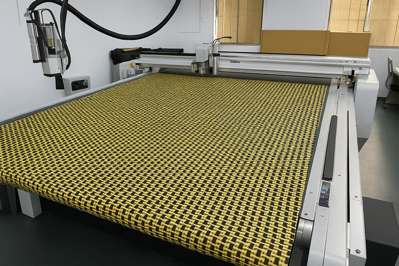 黃色 Kevlar 抗彈布平鋪於數位切割機床台上,準備進行裁切